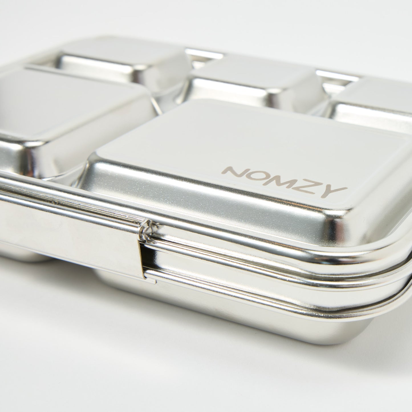 Nomzy stainless steel bento lunchbox with silicone outer sleeve, closed and viewed from side, close up