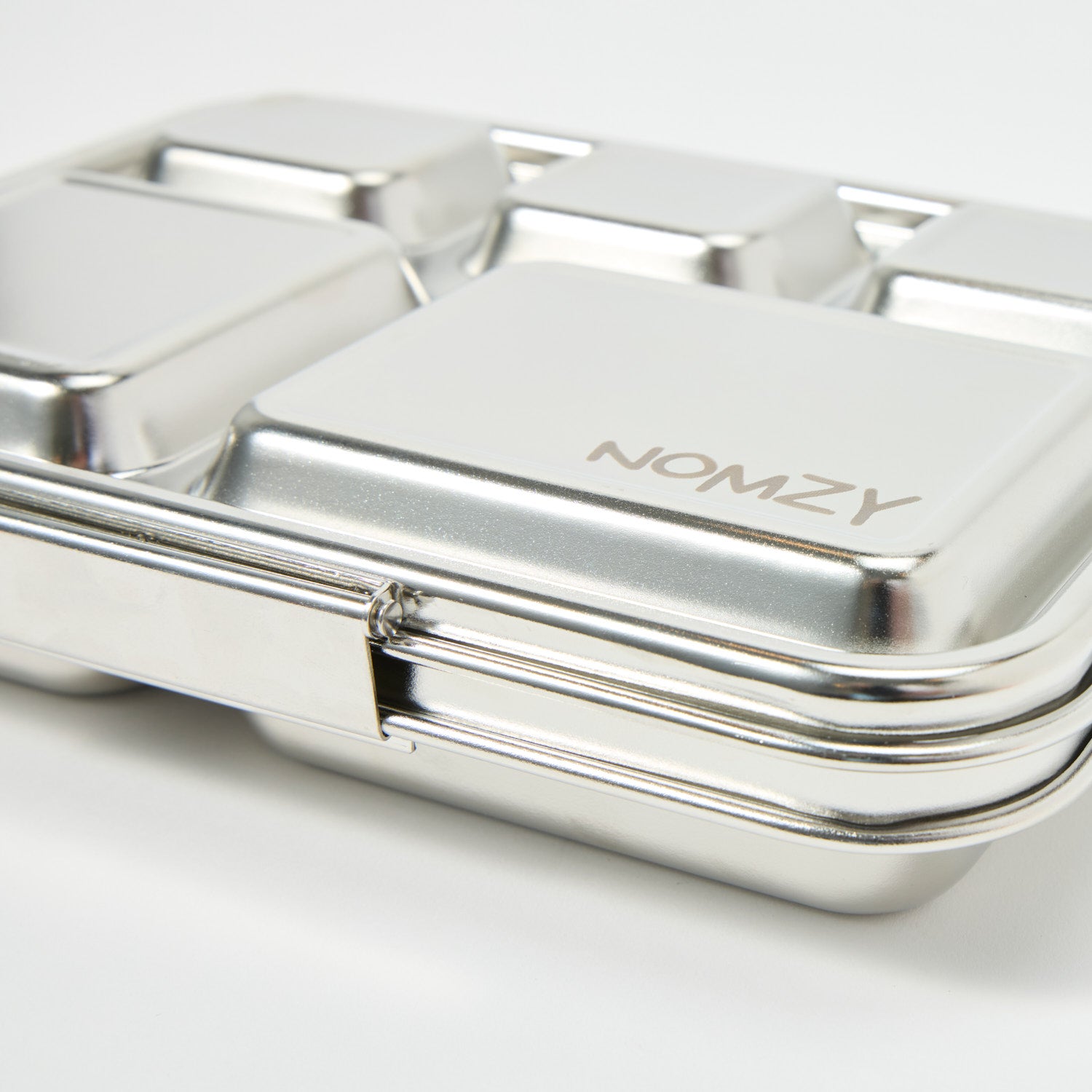 Nomzy stainless steel bento lunchbox with silicone outer sleeve, closed and viewed from side, close up
